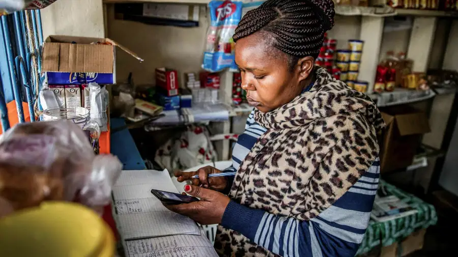 A shopkeeper checking records on a phone