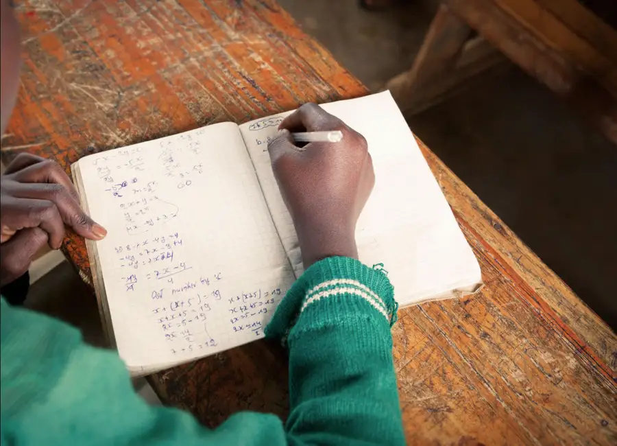 A student writing mathematics in a notebook